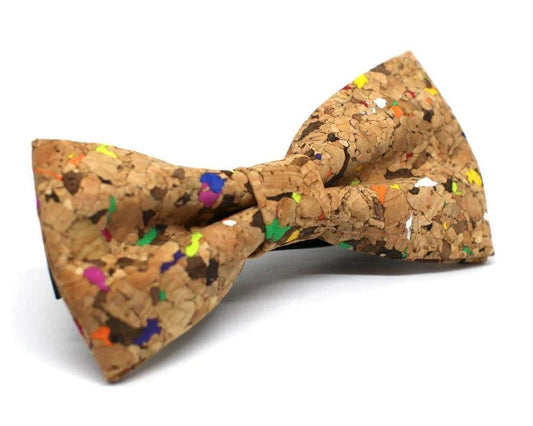 Pajarita de corcho multicolor con motas en tonos verdes, azules, naranjas y amarillos, sobre fondo blanco