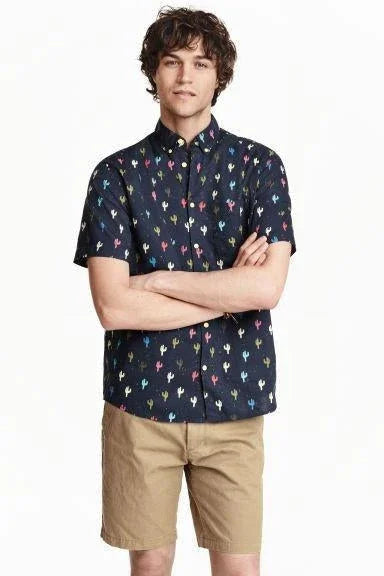 Hombre con camisa azul oscuro estampada de cactus coloridos y shorts beige casual para verano
