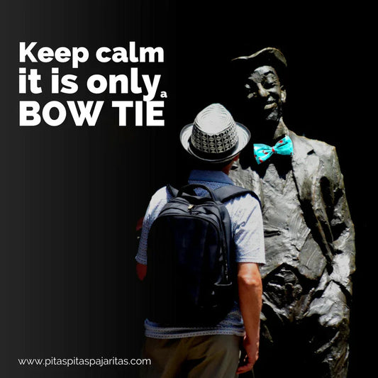 Hombre con sombrero y mochila frente a estatua con pajarita azul turquesa, texto Keep calm it is only a bow tie