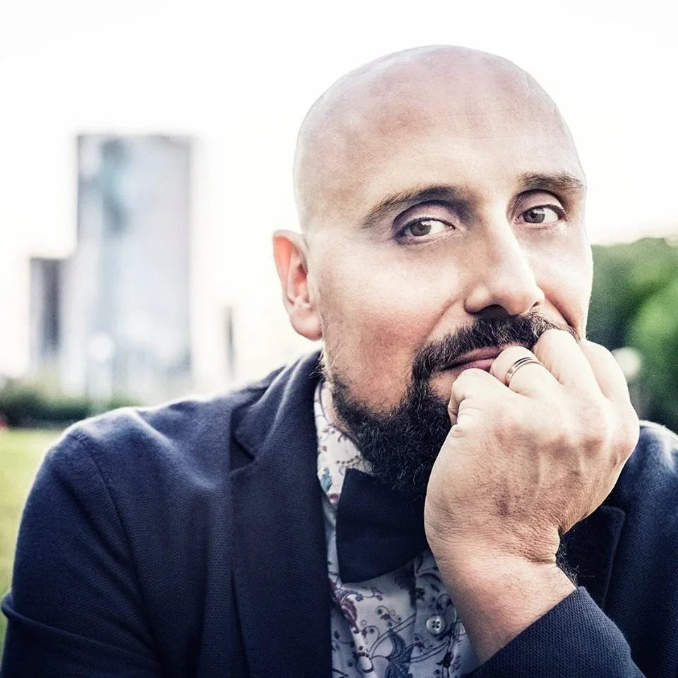 Hombre calvo con barba viste pajarita negra y chaqueta azul en exterior urbano con fondo desenfocado